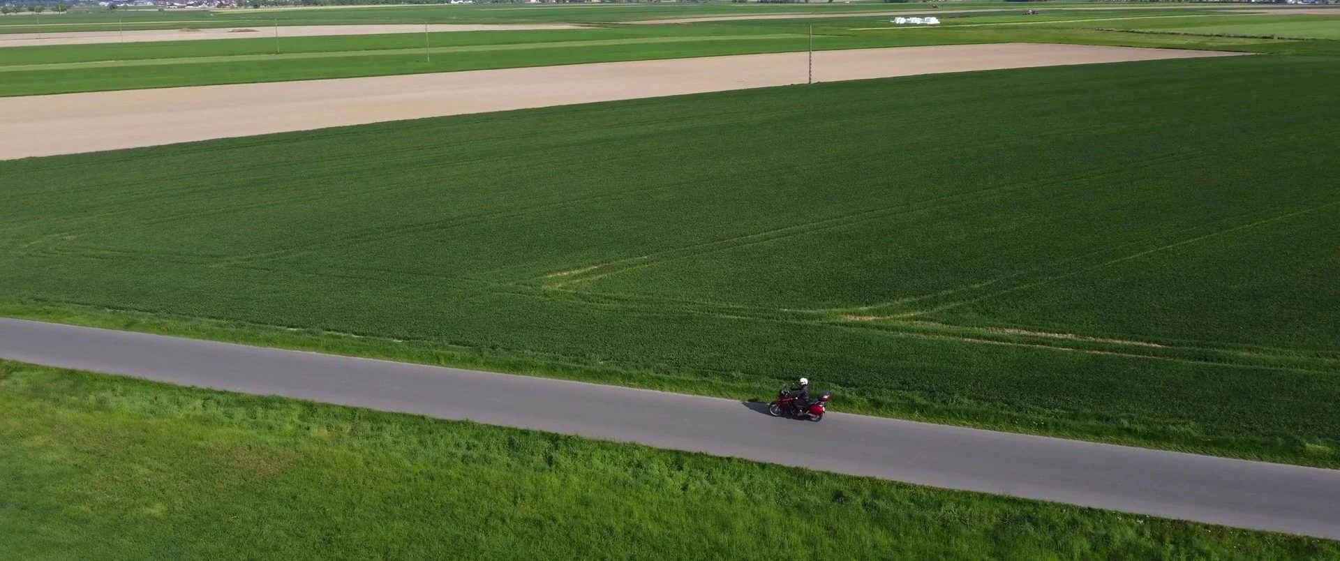Green fields and a road with a motorbike, original footage